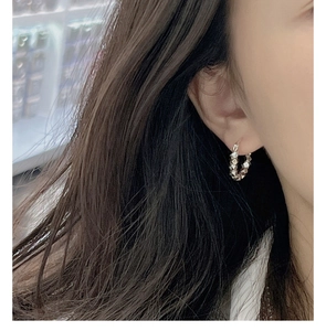 Detail view of silver irregular hammered texture hoop earrings worn on a model