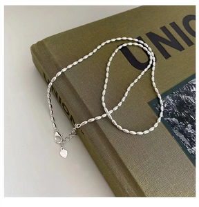 Close-up of 925 sterling silver rice bead necklace with heart pendant on book