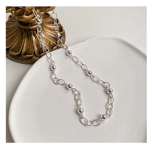 Gros plan détaillé du collier à billes en argent sterling S925 sur plateau blanc