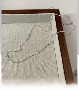 Detail of S925 sterling silver rainbow bead necklace on a dark wooden display tray