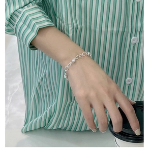 Detailed view of a minimalist 925 sterling silver beaded link bracelet on a wrist
