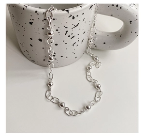 Collier en argent poli élégamment posé sur une tasse en céramique pour un style moderne