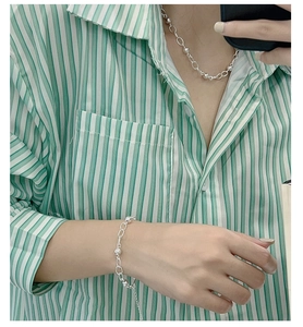Detail view of a 925 sterling silver beaded chain necklace and bracelet set on a model