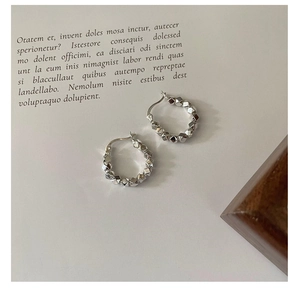 Macro detail of textured geometric faceted silver hoop earrings with metallic luster
