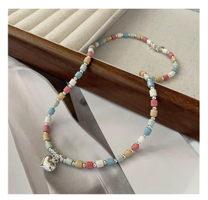 Close-up of heart pendant necklace with macaron ceramic beads on a silk background