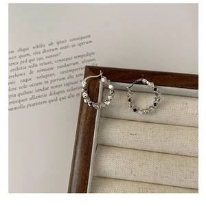 Close-up of S925 sterling silver geometric hoop earrings with reflective faceted design