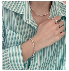 Mannequin portant une parure en argent avec pierres colorées et perles pastel sur fond rayé