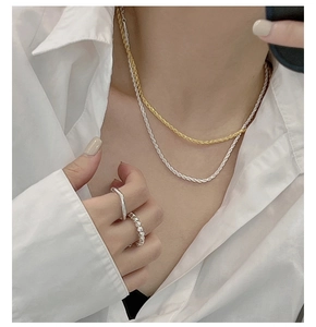 Detailed view of layered silver and gold rope chains with textured geometric rings
