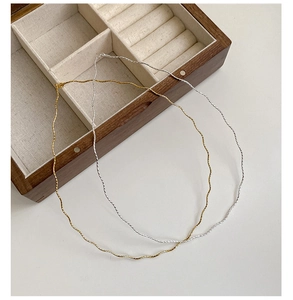 Detailed close-up of gold and silver S925 sterling silver wavy necklaces in a wooden box