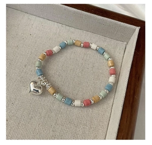 Macro view of multi-color beads necklace with silver heart pendant on a display tray