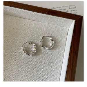 Detail of s925 silver beaded hoop earrings with geometric square cubes on a wooden tray