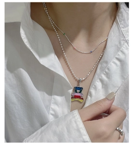 Detail of a double-layered S925 silver necklace with a colorful bear pendant and beads