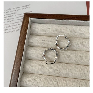 Detailed close-up of s925 silver hoop earrings with geometric square rivet studs on velvet