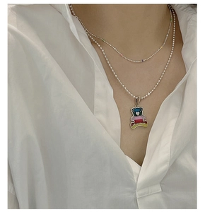 Close-up of double-layered silver necklace featuring a rainbow enamel bear pendant