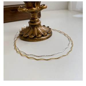 Close-up of S925 sterling silver wave chains in gold and silver on a vintage base