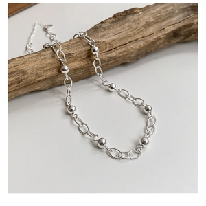 Gros plan du collier de perles en argent sterling S925 sur un support en bois texturé