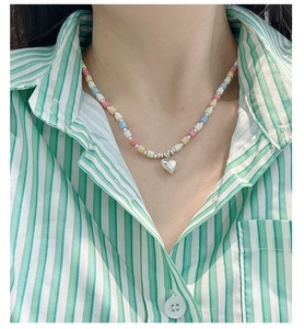 Close-up of a colorful beaded necklace with a silver heart pendant on a model