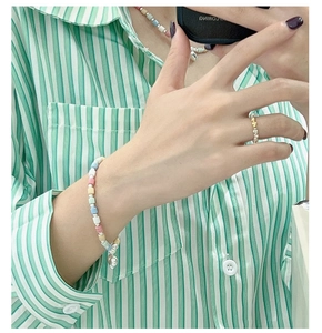 Detail of colorful macaron bead jewelry set with a silver heart pendant on green shirt