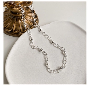 Détail d'un collier de perles en argent sterling S925 sur un plateau blanc minimaliste