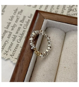 Détail macro d'une bague géométrique argent et or sur un présentoir en tissu vintage