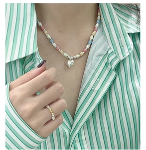 Detail of colorful macaron beaded necklace with silver heart pendant on a model