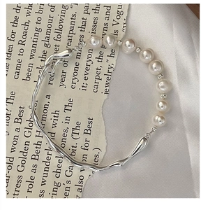 Macro shot of S925 silver irregular liquid metal and white pearl link bracelet on silk
