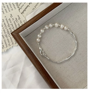 Close-up of S925 silver irregular wave bar and elegant pearls on minimalist bracelet