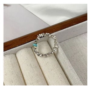 Detail of handcrafted elastic silver bead ring featuring turquoise and spotted stones