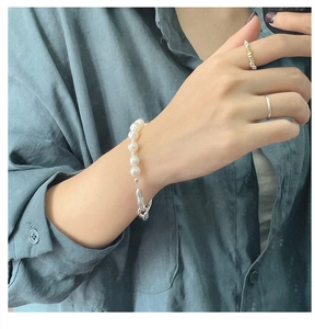 Détail d'un bracelet en perles d'argent avec fermoir métallique porté sur le poignet