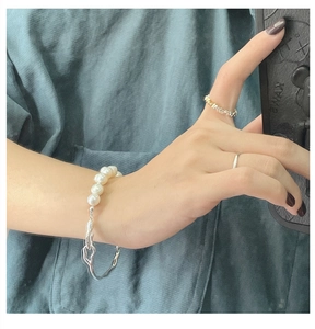 Detail of S925 silver irregular chain bracelet with white pearls and mixed metal rings