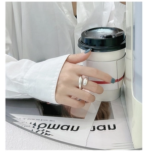Close-up of minimalist S925 sterling silver irregular open ring on model holding coffee
