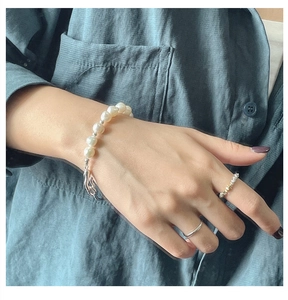 Detail of S925 silver irregular clasp pearl bracelet and rings on a model wrist