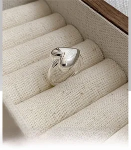 Macro shot of polished S925 sterling silver heart ring set in a beige linen jewelry box