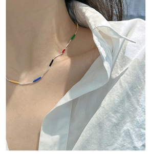 Close-up of colorful enamel bead necklace on model with vibrant rainbow silver tubes