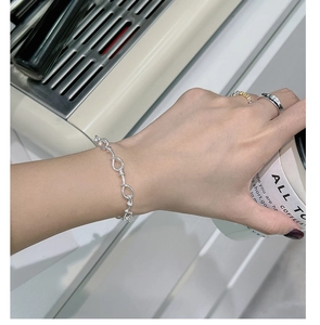 Detail of 925 sterling silver twisted knot chain bracelet on woman wrist with coffee cup