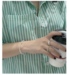 Detail of 925 sterling silver knotted chain bracelet on model with casual stripe shirt