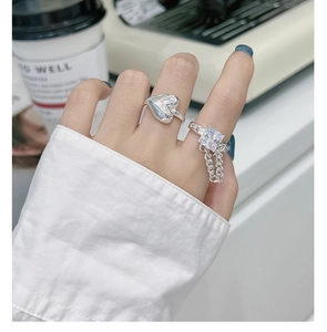 Close-up of S925 sterling silver heart ring and square gemstone chain ring stacked