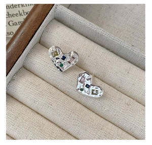 Détail de boucles d'oreilles cœur en argent avec finition martelée et gemmes colorées