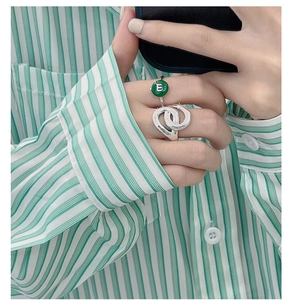Close-up of S925 silver overlapping rings and a green enamel band with letter E