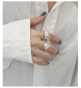 Detail of S925 silver heart ring and square zircon chain ring set worn on finger