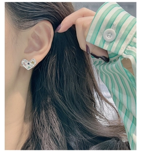 Gros plan détaillé des puces d'oreilles cœur texturées avec pierres fines sur un modèle