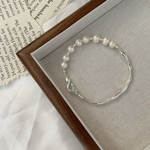 Minimalist S925 silver wavy bracelet with lustrous pearls on a vintage background