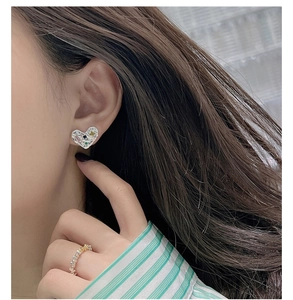 Détail d'une boucle d'oreille cœur en argent avec pierres colorées sur modèle