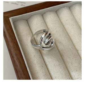 Close-up of S925 sterling silver twisted ring with a polished finish in a beige box