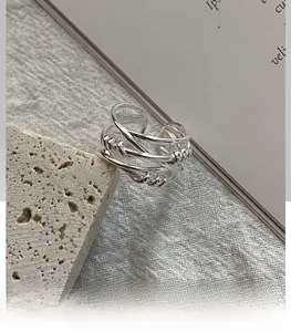 Detailed view of silver multi-layer intertwined ring on a rustic stone and fabric setting