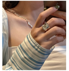 Detailed mirror selfie showing a wide wavy liquid silver ring on model finger
