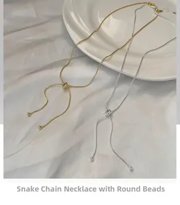 Macro detail of adjustable silver and gold snake bone necklaces on white silk