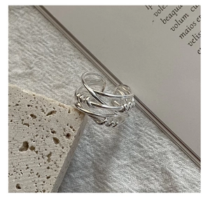 Macro detail of multi-layer twisted rope S925 silver ring on a textured stone surface