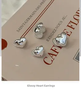 Macro shot of polished S925 sterling silver heart-shaped hoop earrings on vintage book