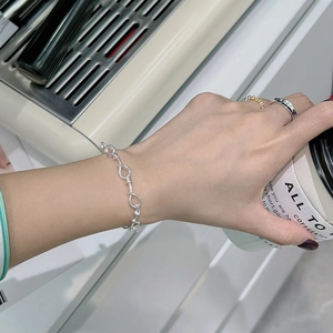 Minimalist 925 sterling silver knotted rope bracelet shown on model with urban cafe backdrop